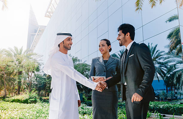 Business professionals shaking hands outside modern office building in KIZAD Free Zone.