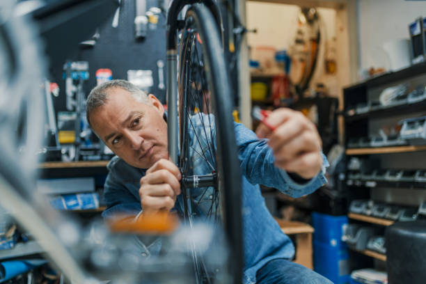 Small business owner repairing a bicycle wheel in a cluttered workshop, representing essential tools for success.